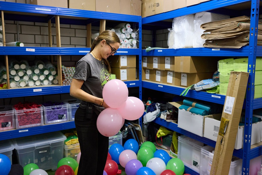 Mitarbeiterin mit aufgeblasenen, bunten Luftballons im Lager des Indoorspielplatz Tummel Dschungel