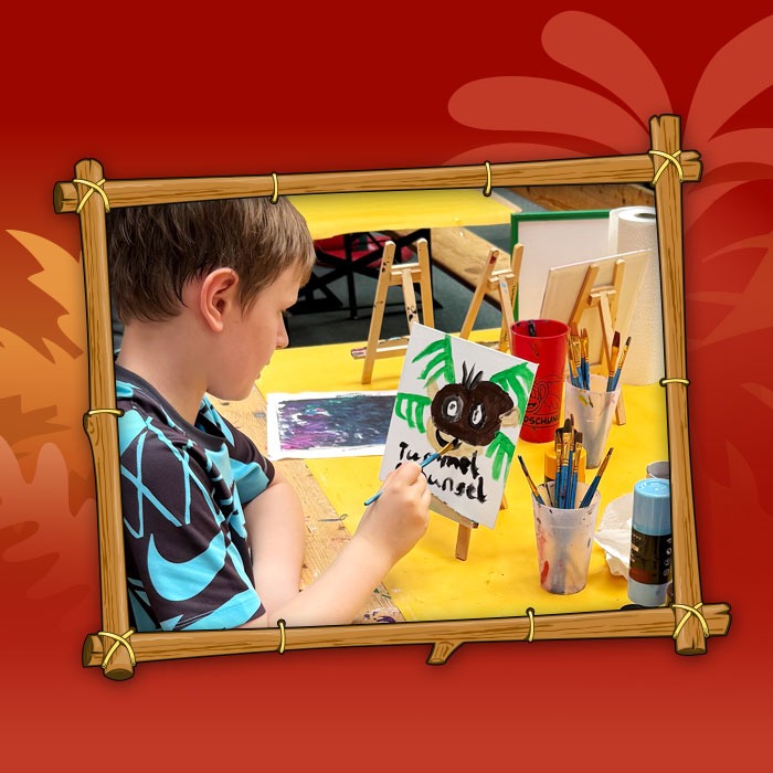 Junge bemalt Leinwand beim Basteln in den Herbstferien im Indoorspielplatz